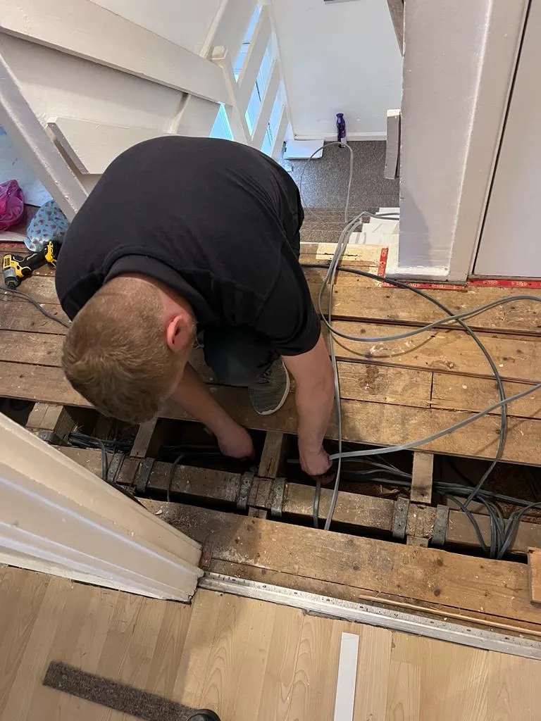/electrician Passing Cable Under Wooden Flooring